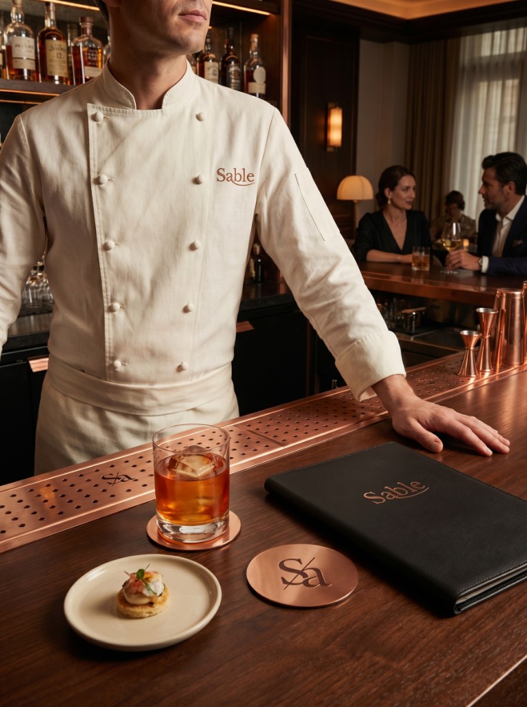 Sable restaurant bar: embroidered coat, leather menu, copper coasters with monogram, cocktail on wood