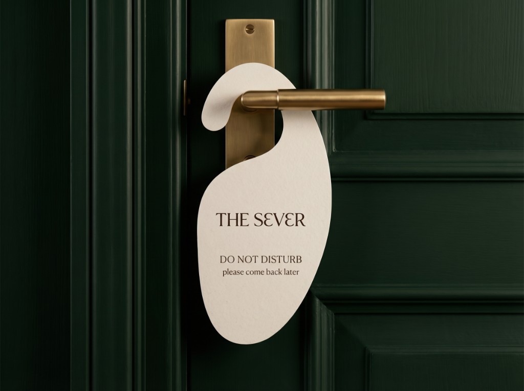 The Sever cream door hanger on a forest-green paneled door with brass lever; Do Not Disturb and please come back later
